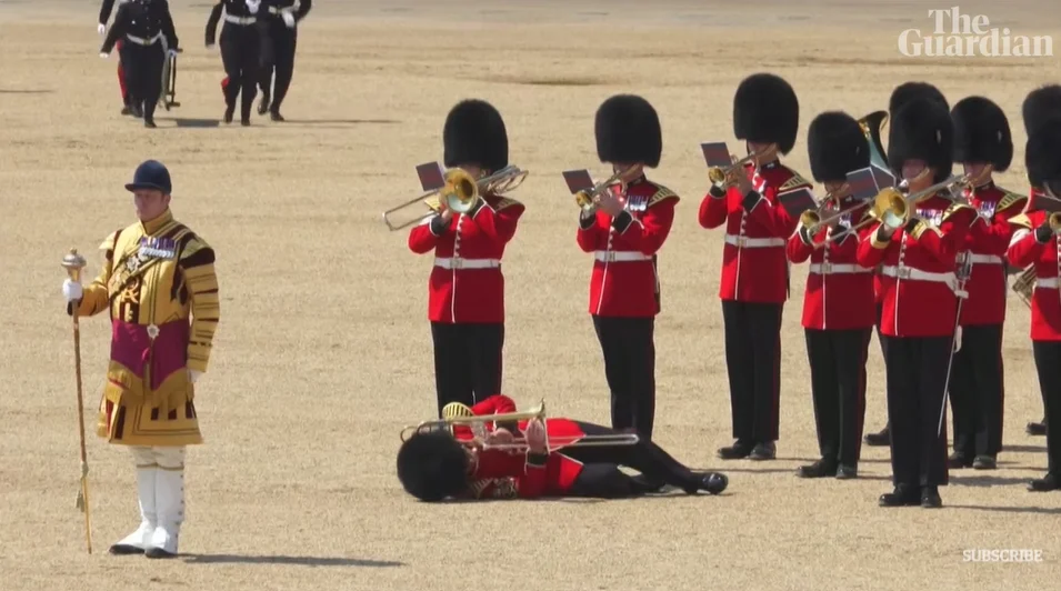 Soldier faints during military parade, but continues playing trombone.