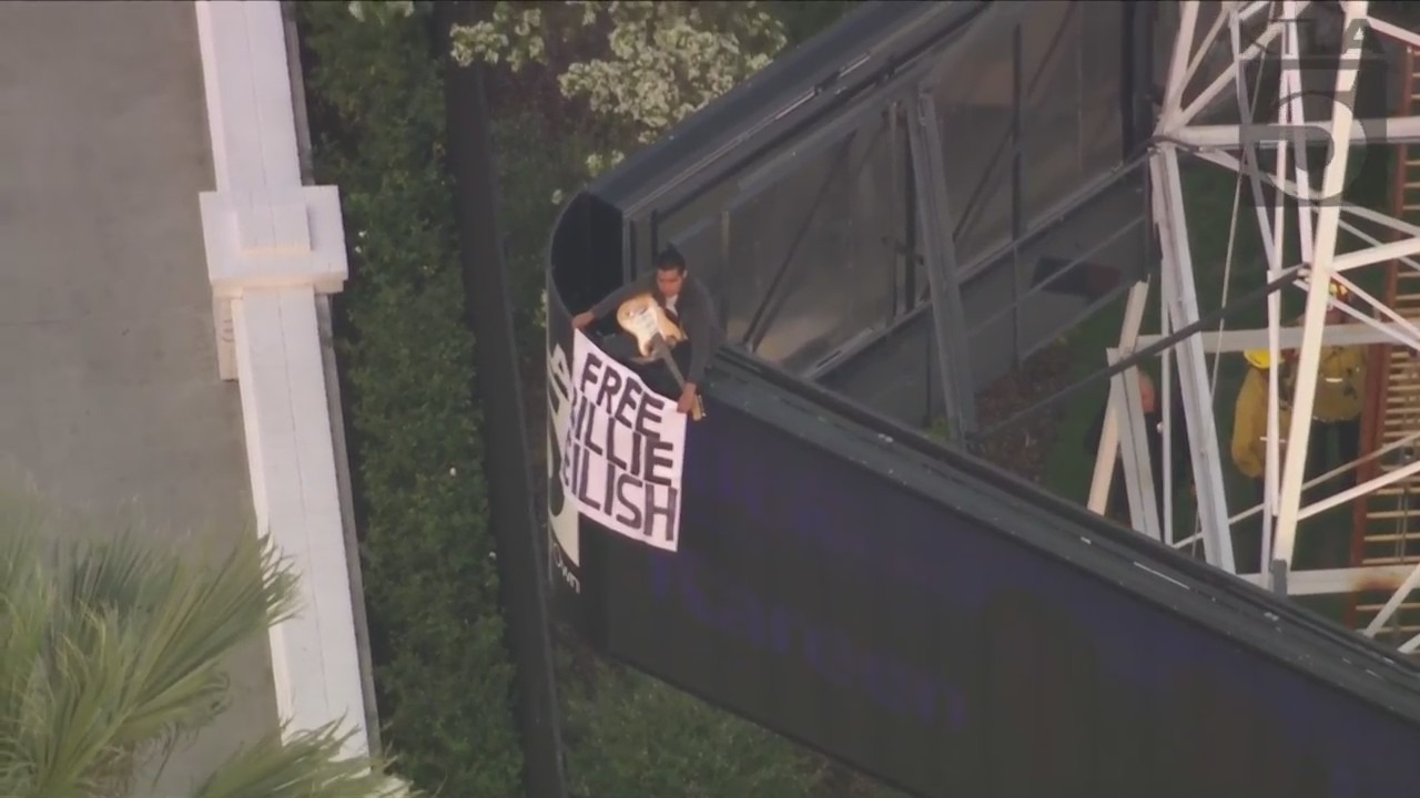 Man scales Hollywood tower with 'Free Billie Eilish' sign.