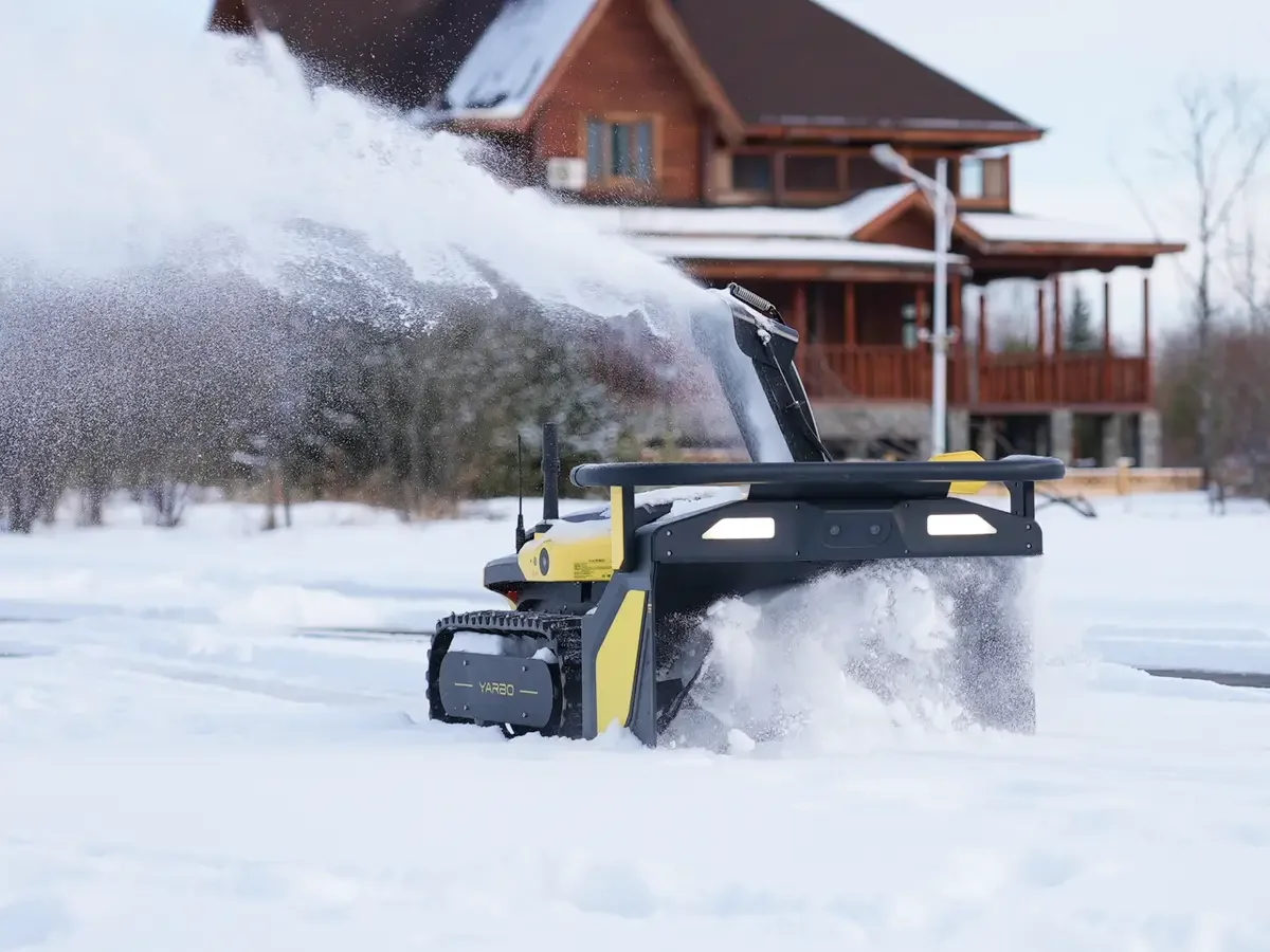 Robot Snow Blower Clears Driveway While Owner Watches from Inside