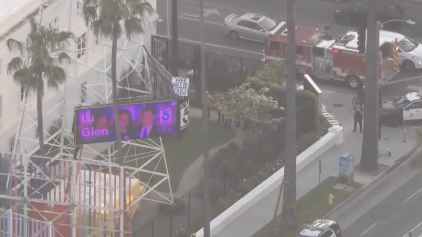Man scales news tower in Hollywood with "Free Billie Eilish" sign.