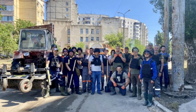 Featured image for Ukrainian utility workers aid in aftermath of dam destruction amidst ongoing conflict with Russia.